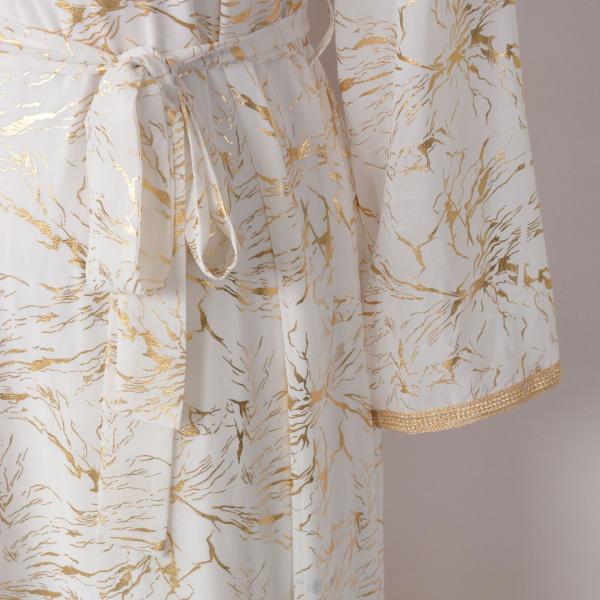 white dress embroidered with gold, a luxury that speaks of femininity