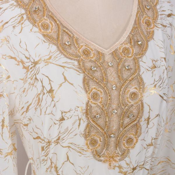 white dress embroidered with gold, a luxury that speaks of femininity