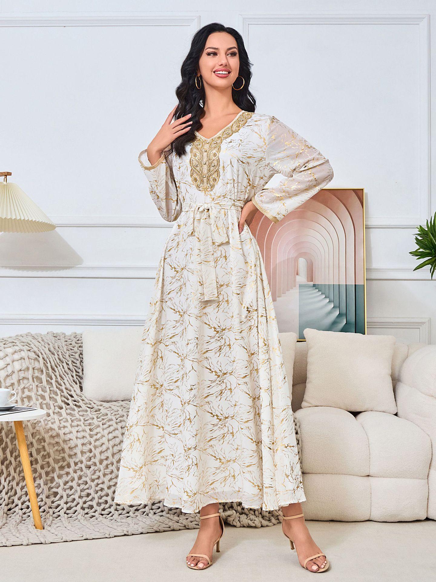 white dress embroidered with gold, a luxury that speaks of femininity